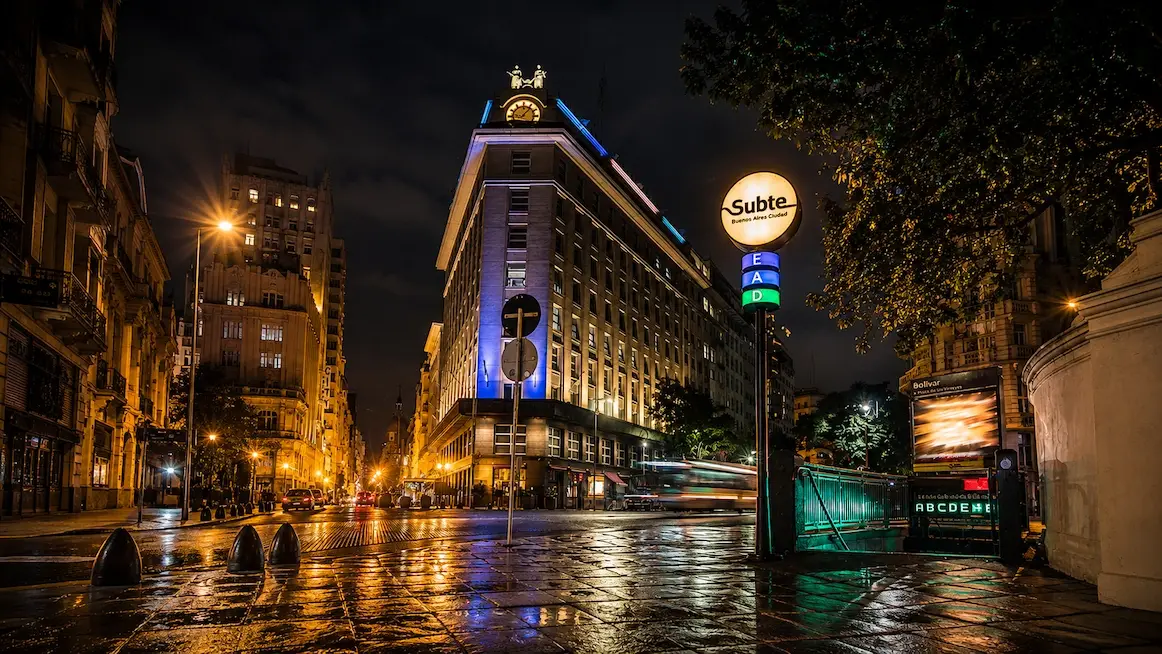 A Subte station entrance glowing on a rainy Buenos Aires night