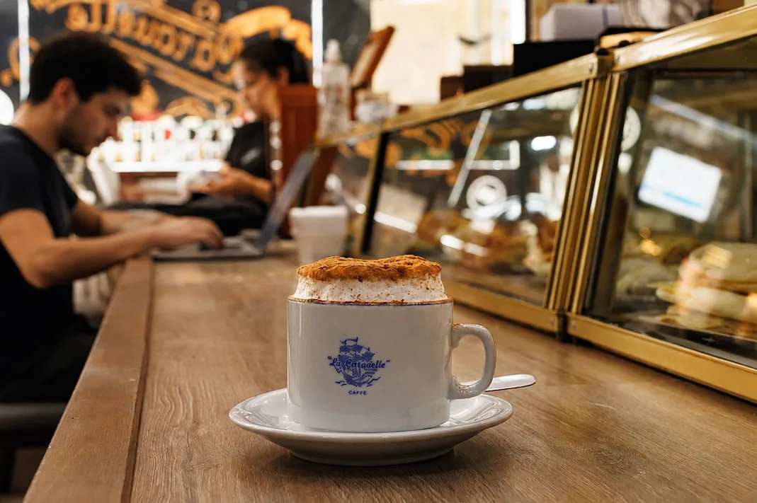 A coffee at the bar of a classic Buenos Aires cafe, laptops open behind