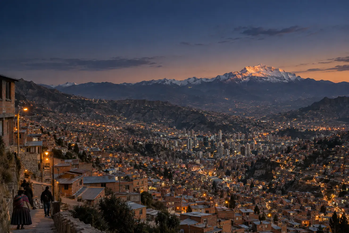 The bowl of La Paz from the El Alto rim at dusk, brick hillsides stepping down to the lights and Illimani's snow behind