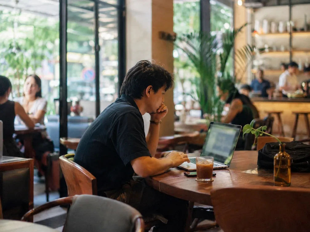 A person works on a laptop in a modern, plant-filled Manila cafe